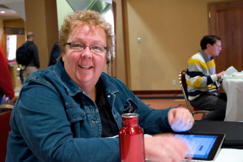 the woman is sitting at the table having an electronic tablet