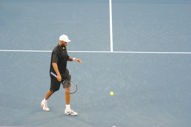 a man in a black shirt holding a racquet and tennis ball