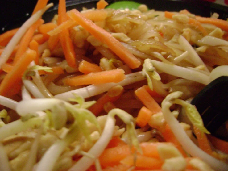 mixed vegetables in a black bowl are being stirred with a grater