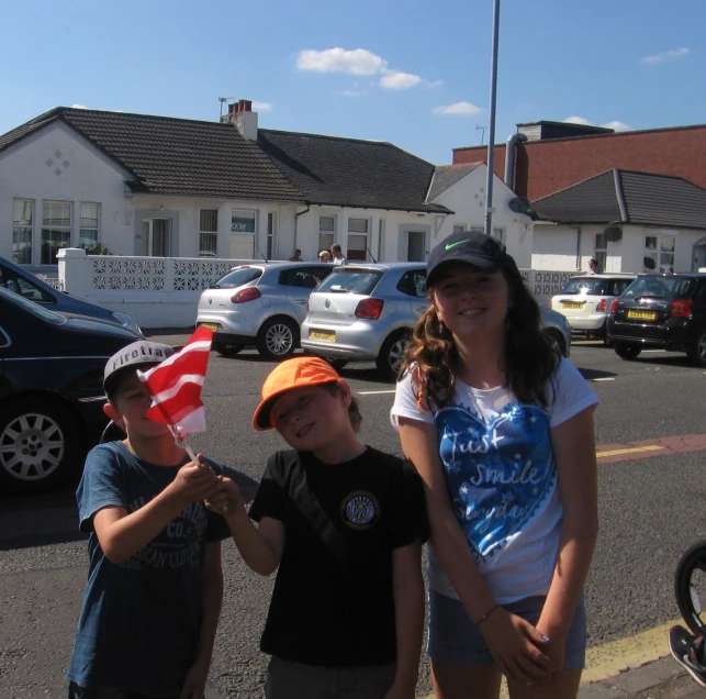 two boys and one girl stand outside with their flags