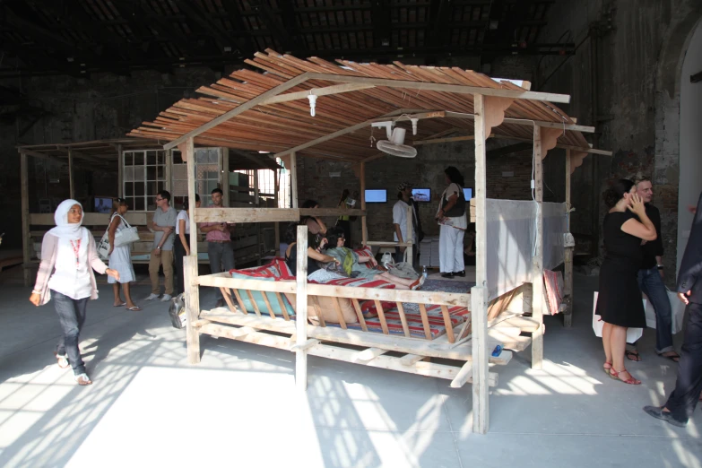 people standing around a makeshift bed outside in the sun