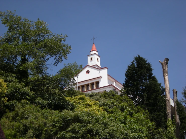 a white church with red roof standing above trees