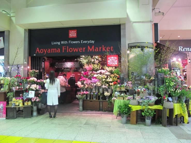 an asian woman walking out of a flower shop