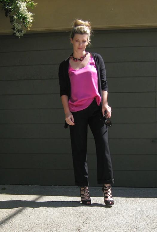 a woman wearing a pink shirt is standing by the garage