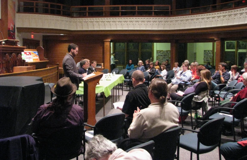 a man speaks to a crowd in front of a podium