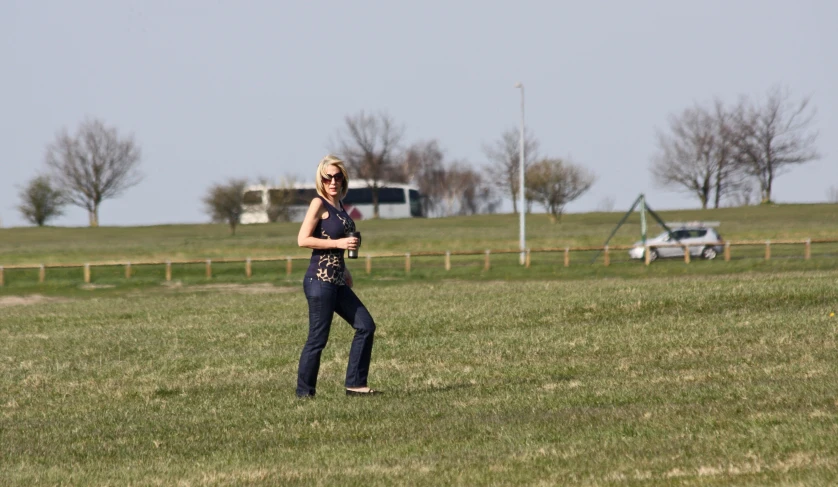 a woman is standing in the middle of a grassy field