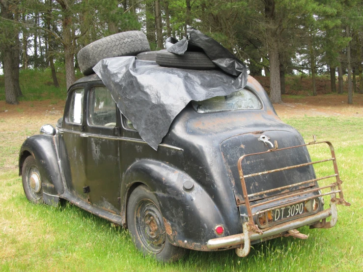 an old, black car with luggage piled on it