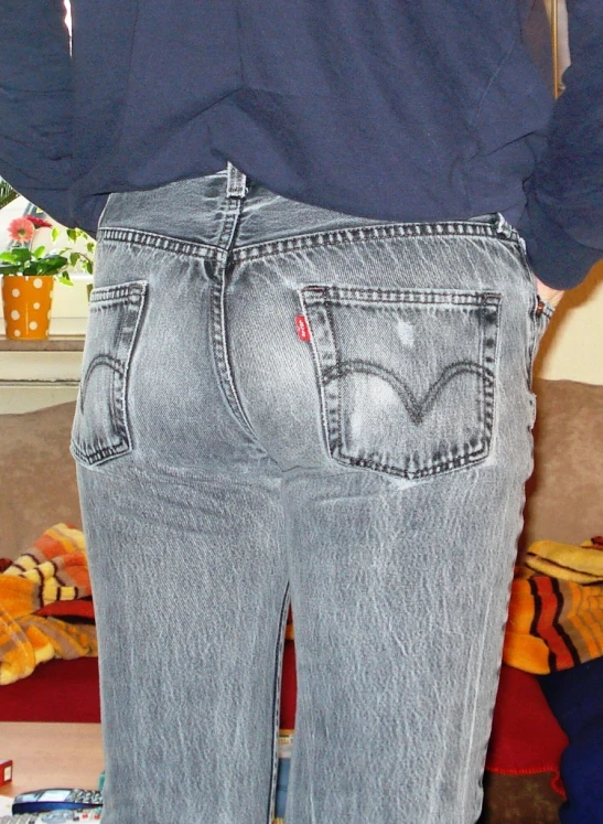 a woman is holding onto her jeans while standing in front of a couch