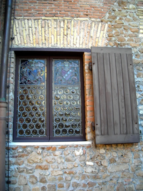 the glass window has wooden shutters next to it