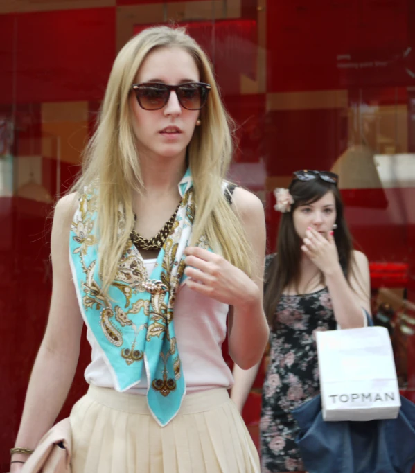 a woman wearing a blue scarf and white skirt walking