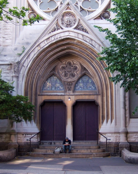 two people sit on steps in front of a large building