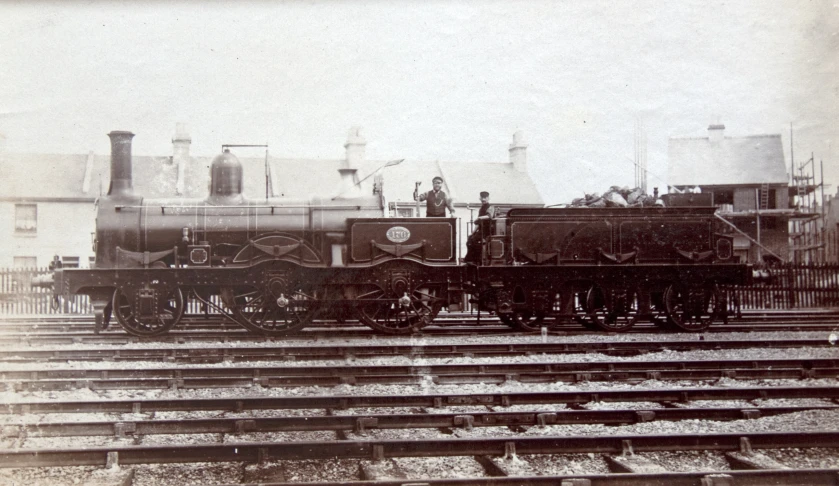 two men standing on top of a train next to train tracks