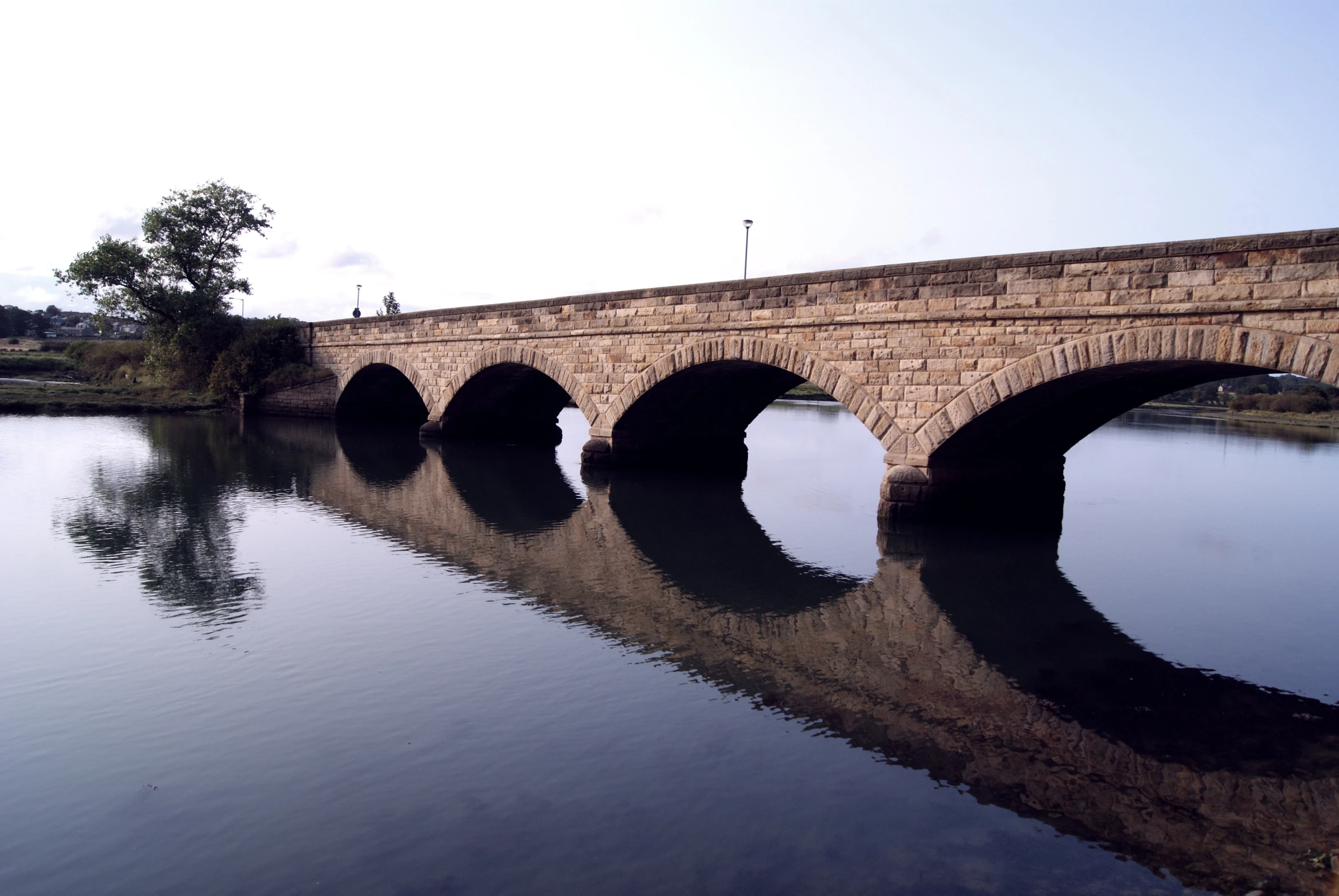 an old stone bridge over a lake