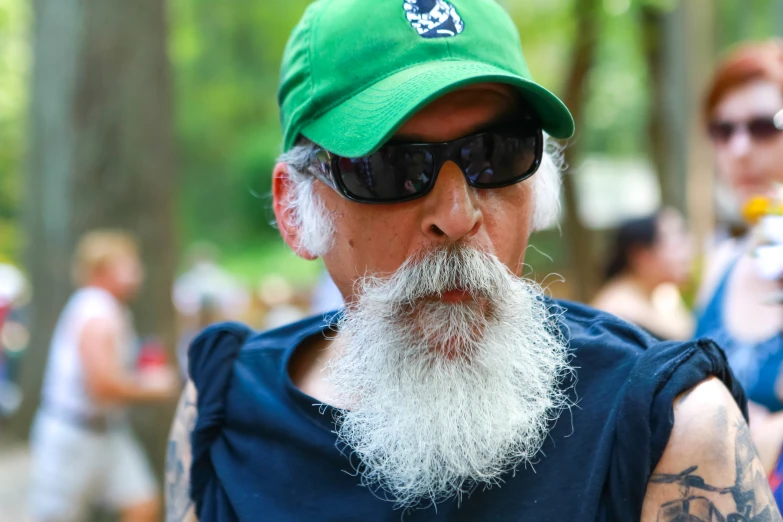 an older man with white beard and tattoos wearing sunglasses and hat