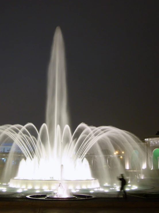 the fountain at night is brightly lit in bright colors