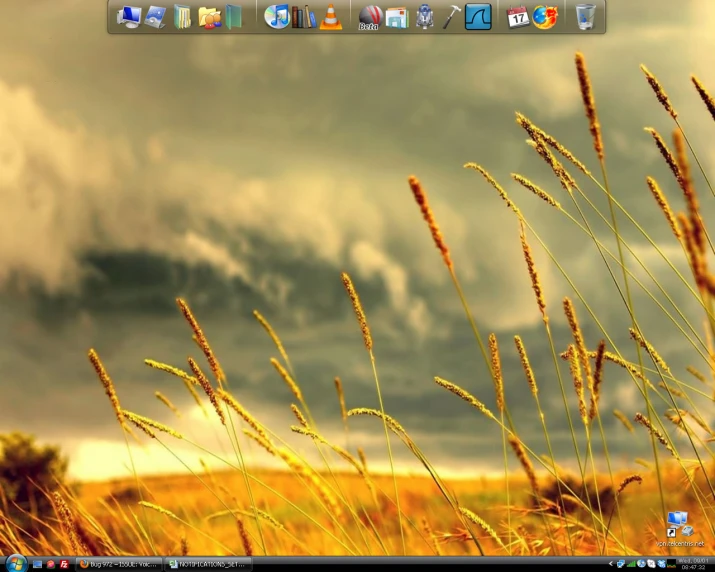 a desktop computer screen with a picture of grass and storm clouds in the background