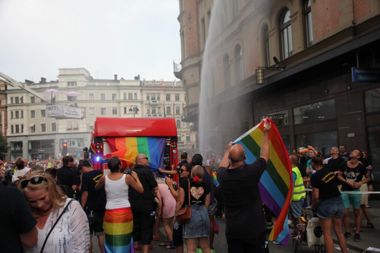 people standing outside in the street with a fire hydrant and rainbow kite