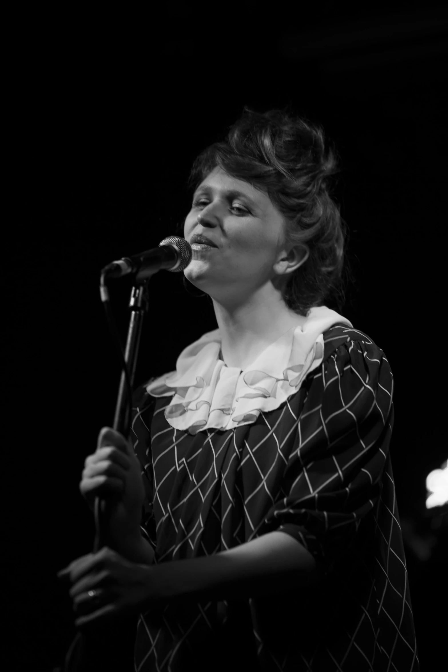 a woman singing into a microphone on stage