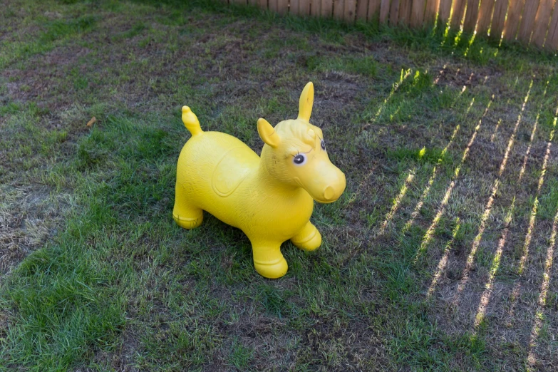 a yellow dog statue sitting in the middle of a grassy yard