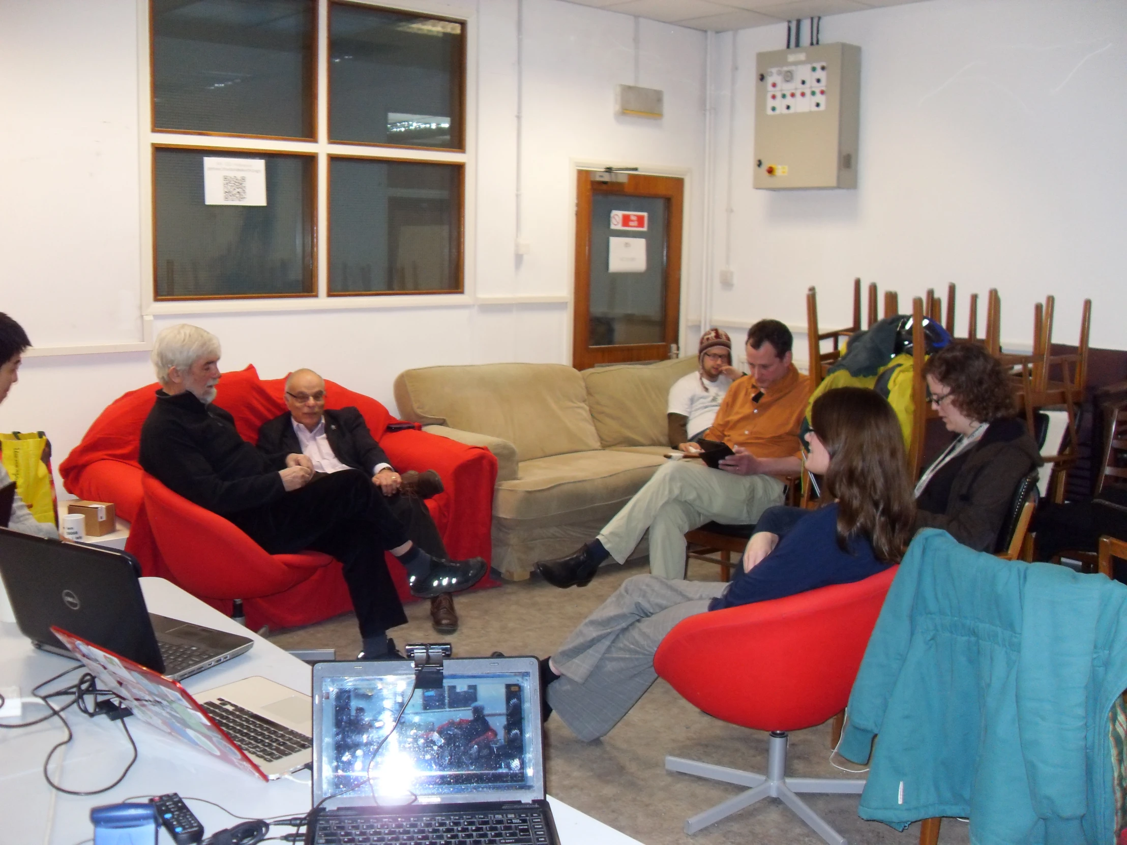 several people sit around a room looking at a computer