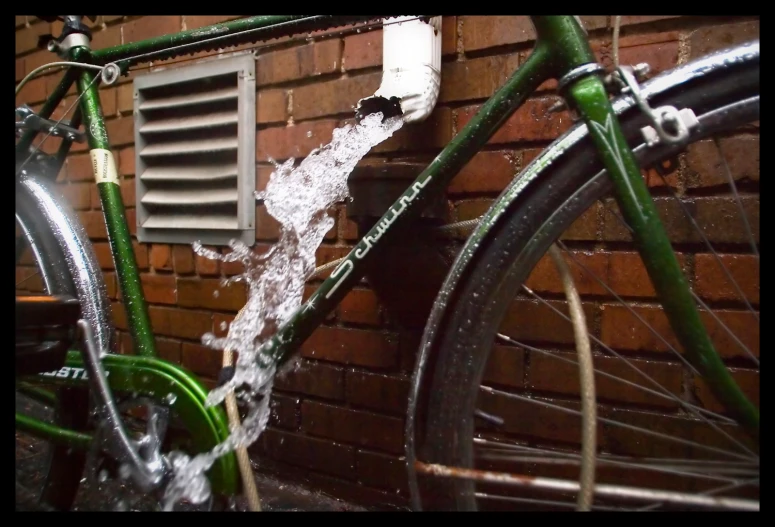 a bike parked near a brick wall and a drain