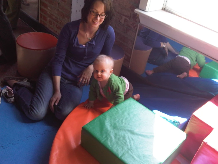 a woman with a baby playing with an inflatable mat