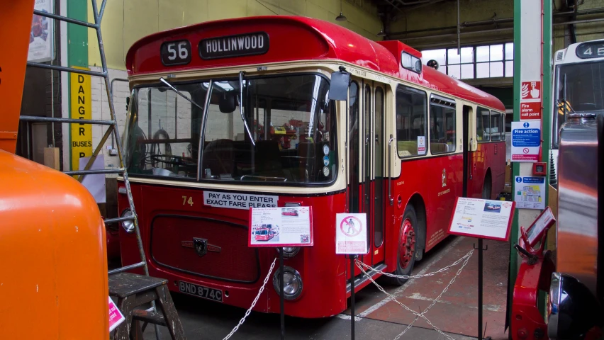 a large red bus is parked next to another orange bus