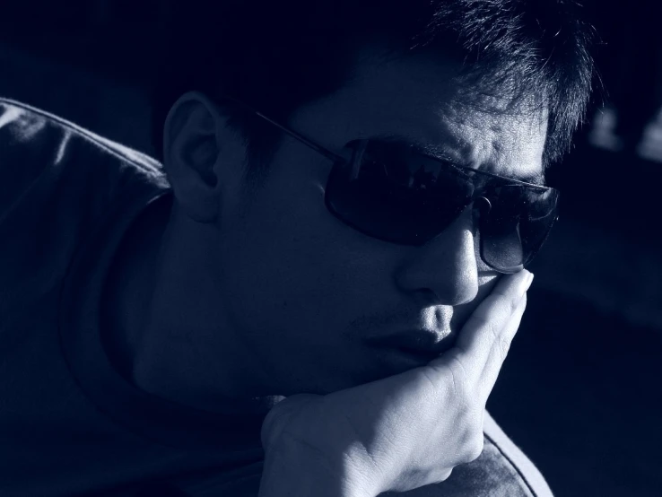 black and white image of a man in sunglasses sitting down