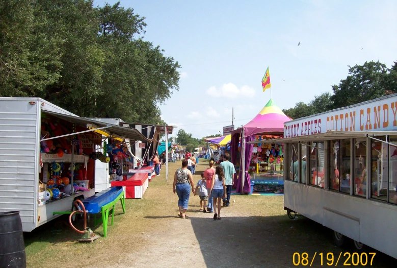 people walking around an outdoor fair with tents