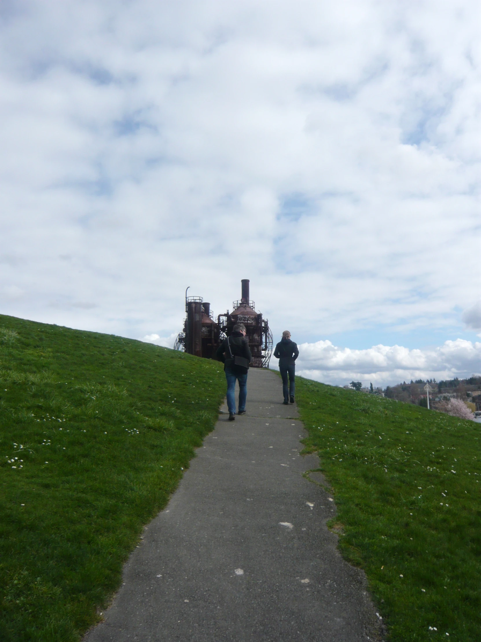 two people are walking up a hill on a road