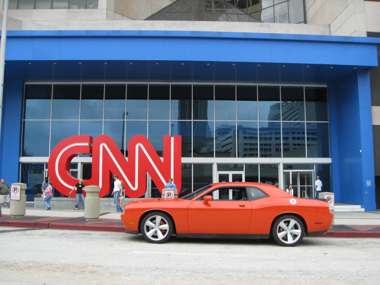 an orange car is parked by the cnn sign