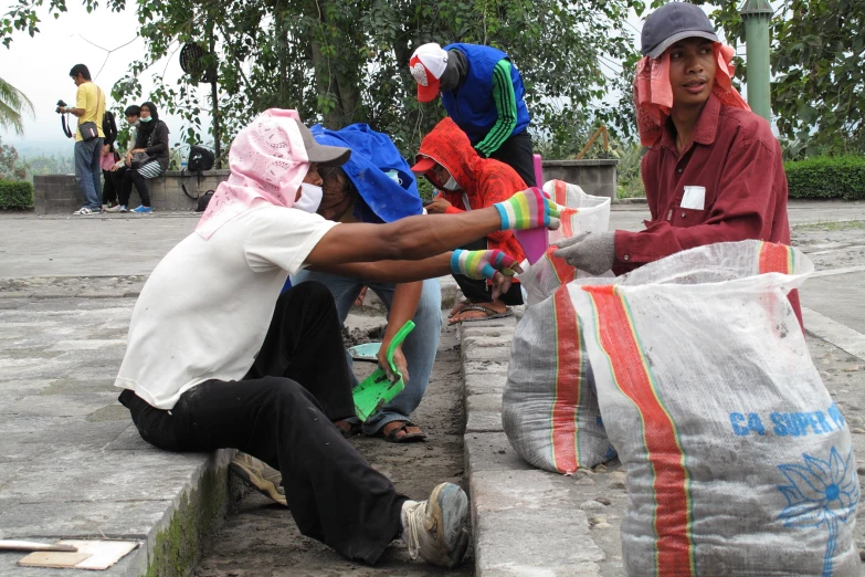 people sitting on concrete bags wearing hoods