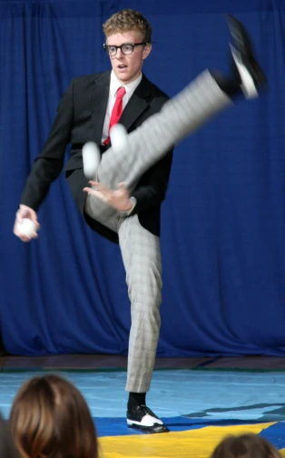 the man in the suit is juggling with a bat