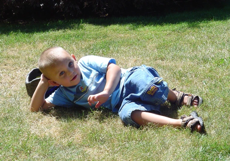 a little boy laying in the grass and smiling