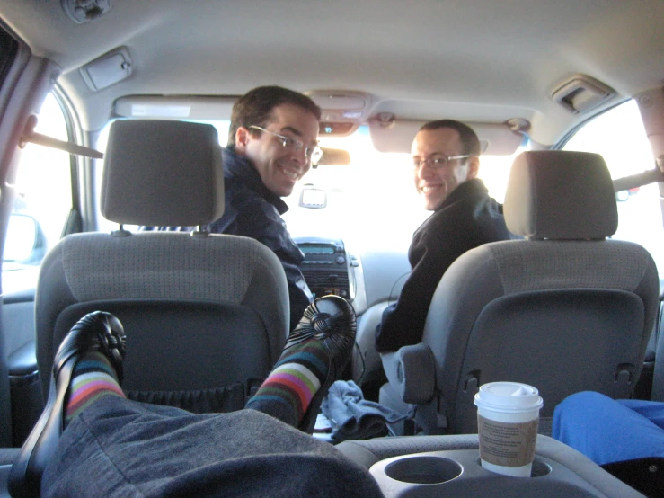 two men sitting in the passenger seat of a vehicle