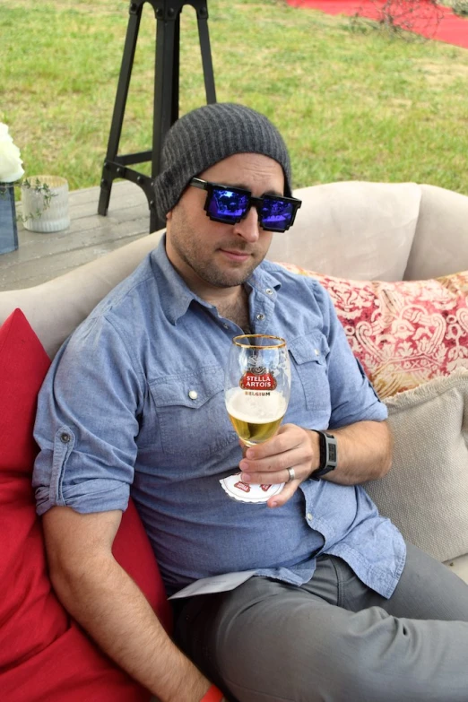 a man sitting on the couch while holding a wine glass