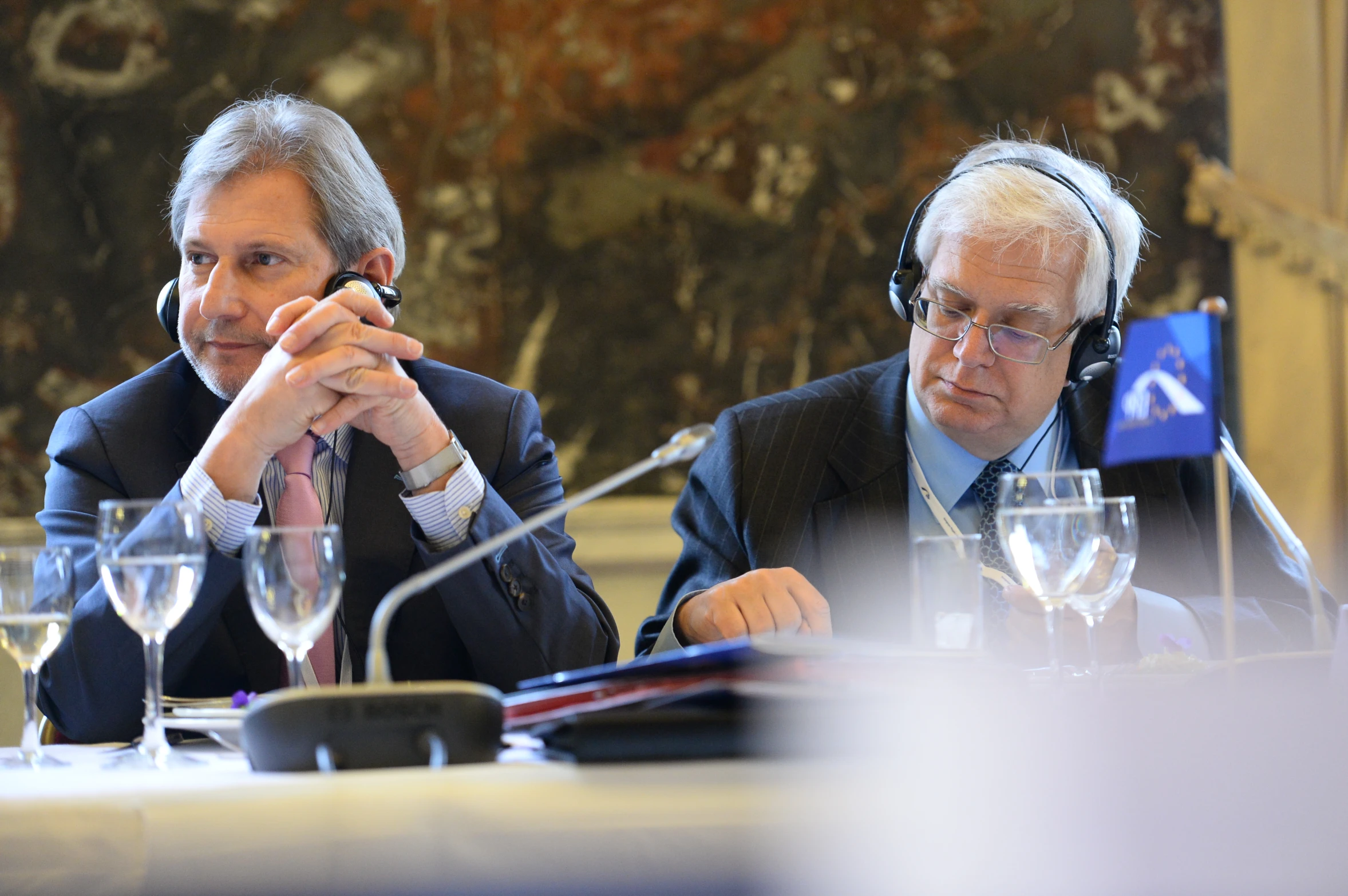 two men in suit and head phones sitting at a table