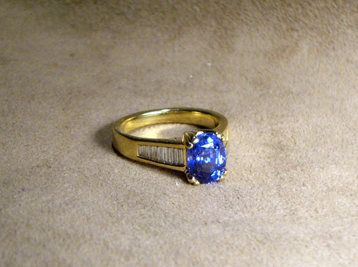 a ring with a blue stone on the top sits on a carpet