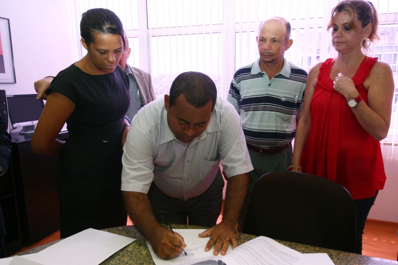 two men standing behind a table and another person looking at paperwork