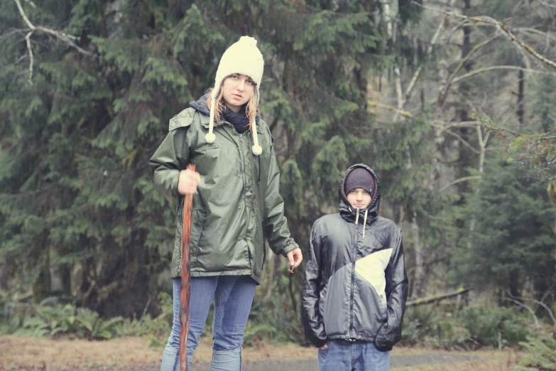 a woman and a boy in the woods while holding ski poles