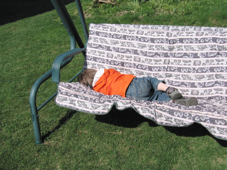 a little boy that is laying down on a bench