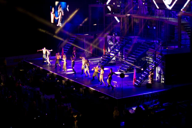 a group of people standing on a stage under a tv