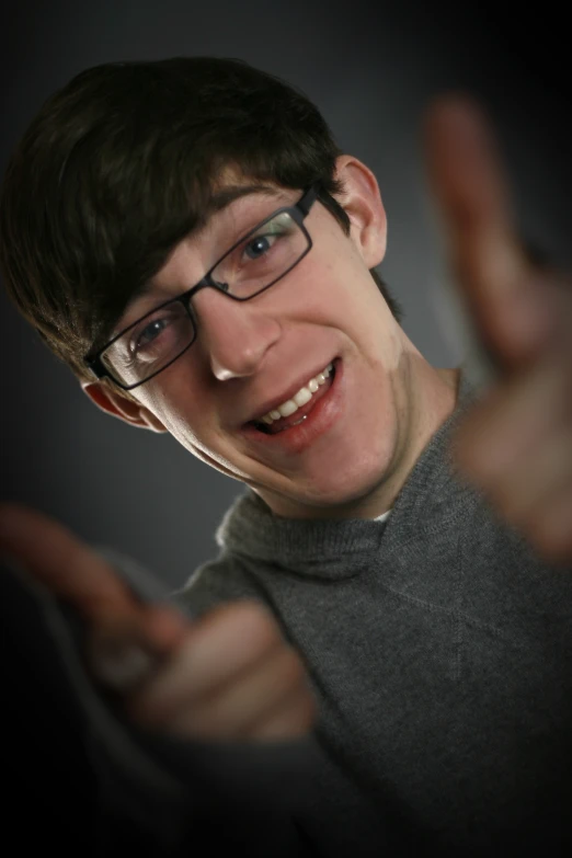 a man with glasses giving a thumbs up