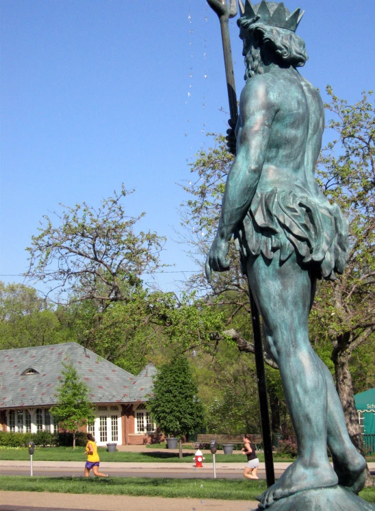 a statue with a staff next to a street