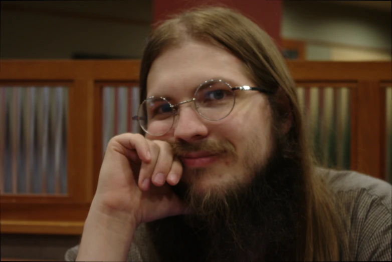 a man wearing a long beard and glasses looks at the camera