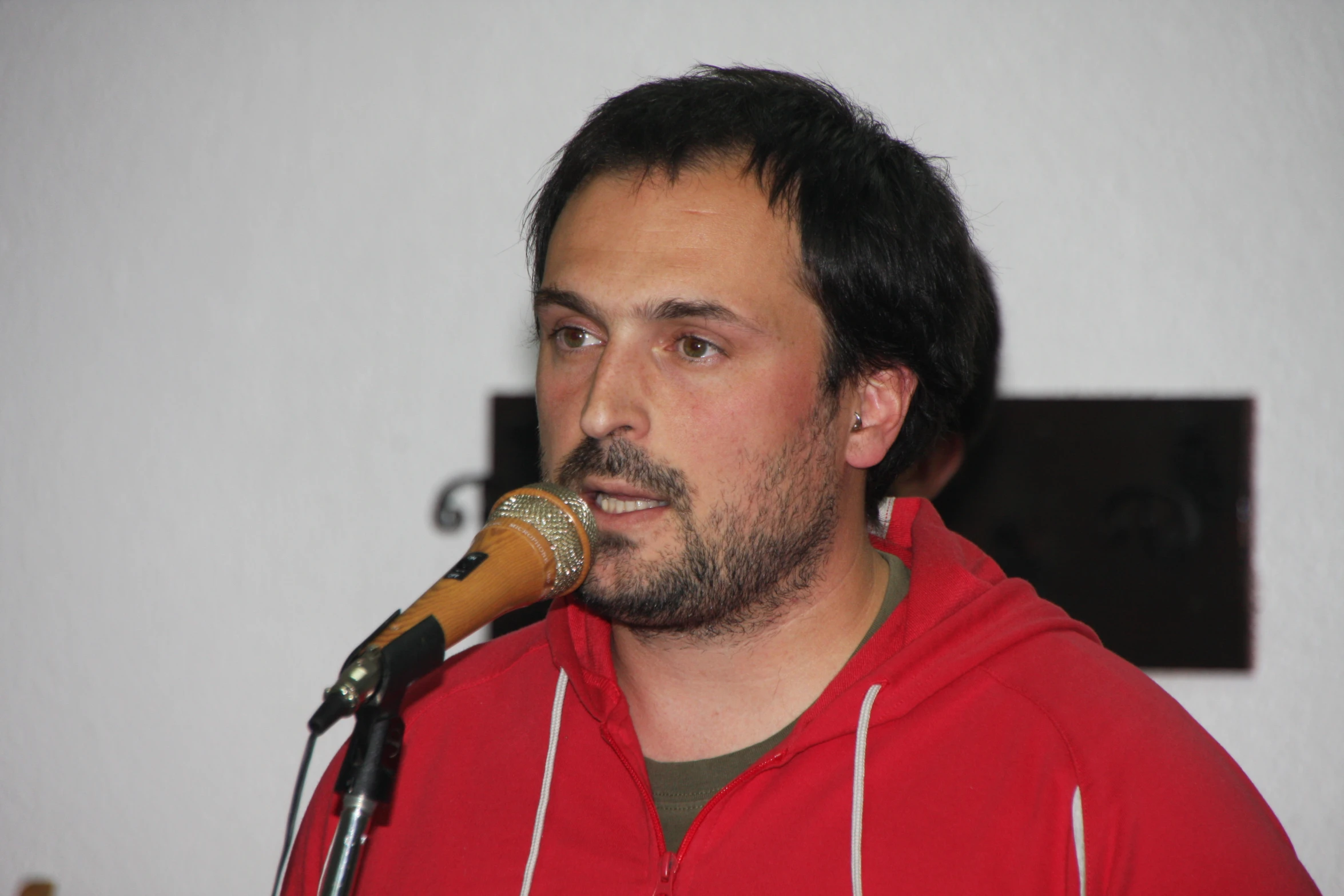 a man wearing a red hoodie holding a microphone