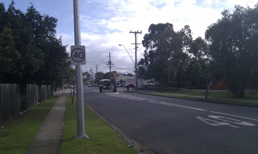 a street sign next to a road with cars parked along the sides of the street