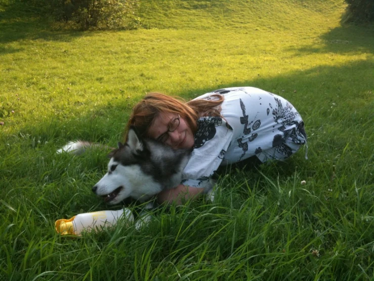 a girl in a dress lays on the grass with her dog