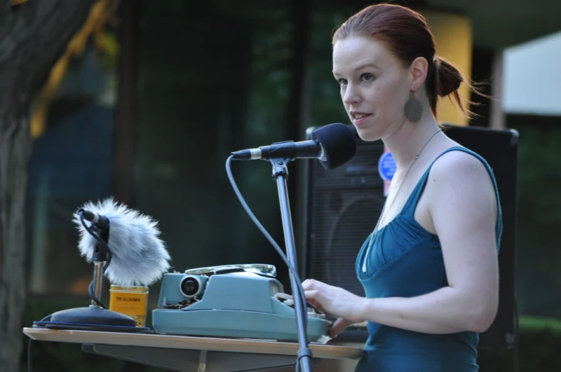 the young woman is holding a microphone and talking into a mic