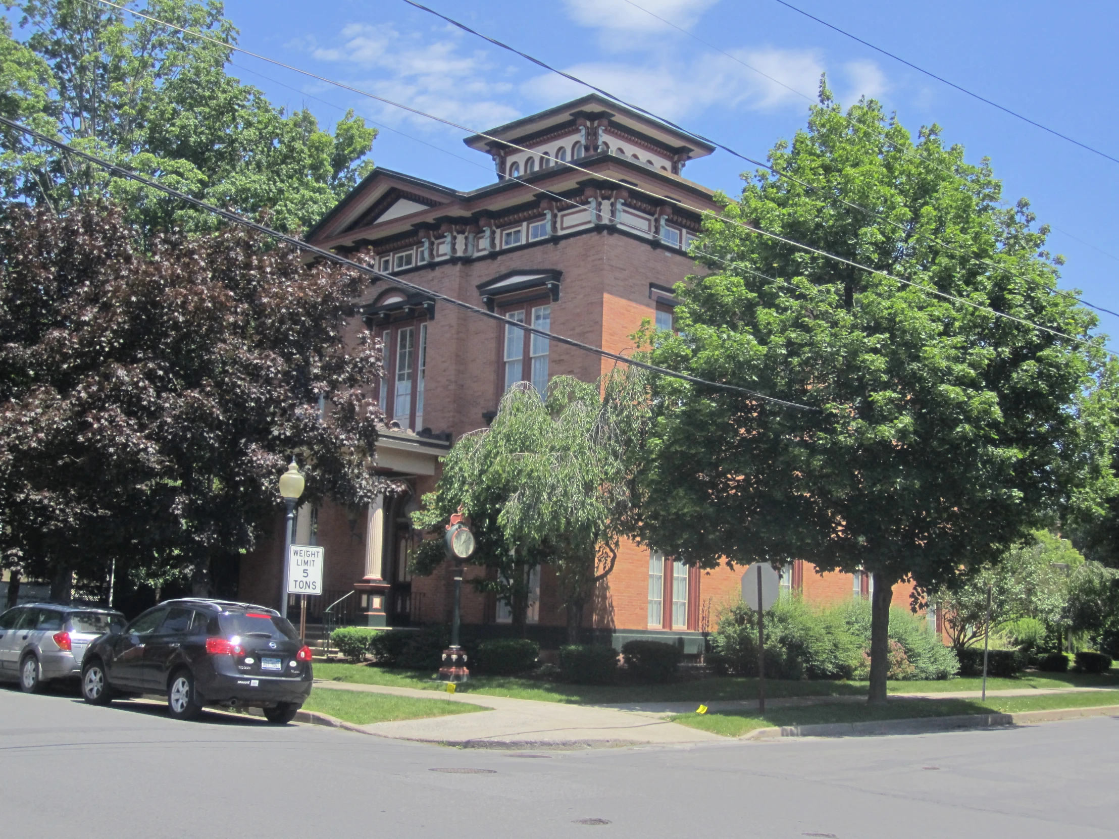 a two story brown brick building sitting next to several parked cars